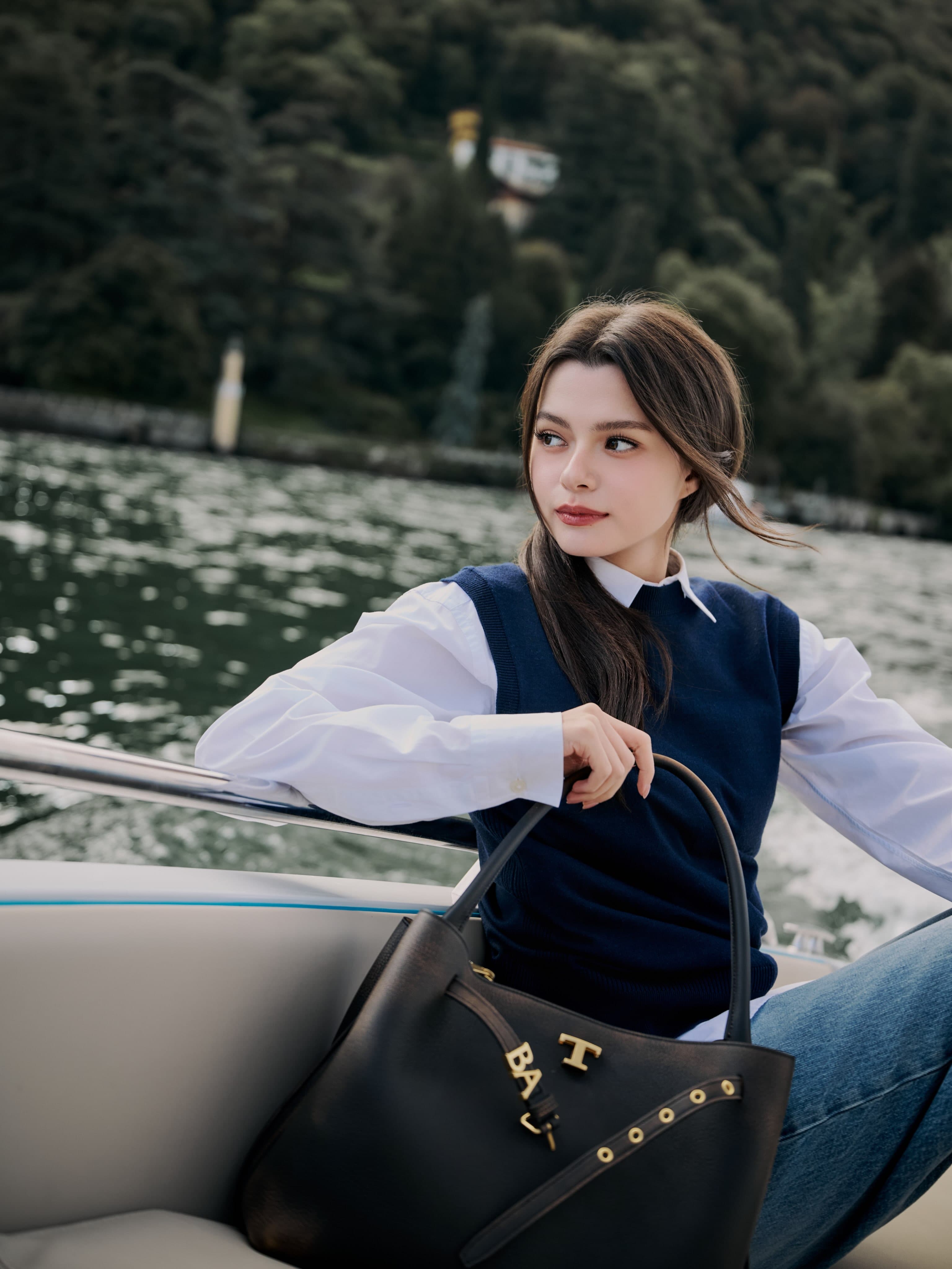 Becky Armstrong by the lake in a navy vest, white shirt and denim