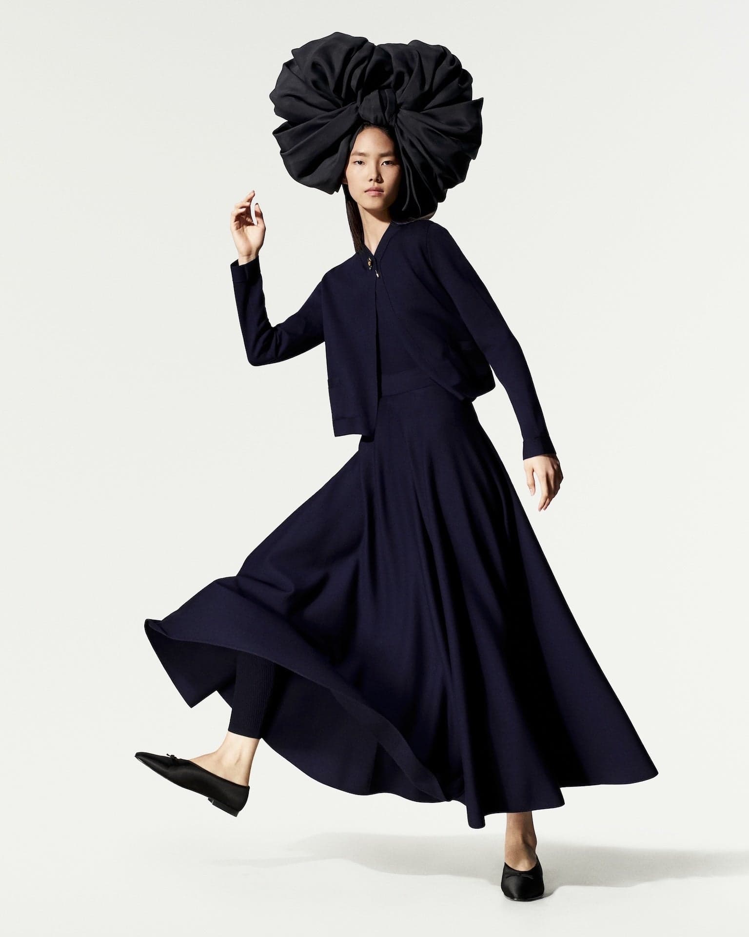 Loro Piana Spring 2027 look: a navy dress with a sculptural dark hat